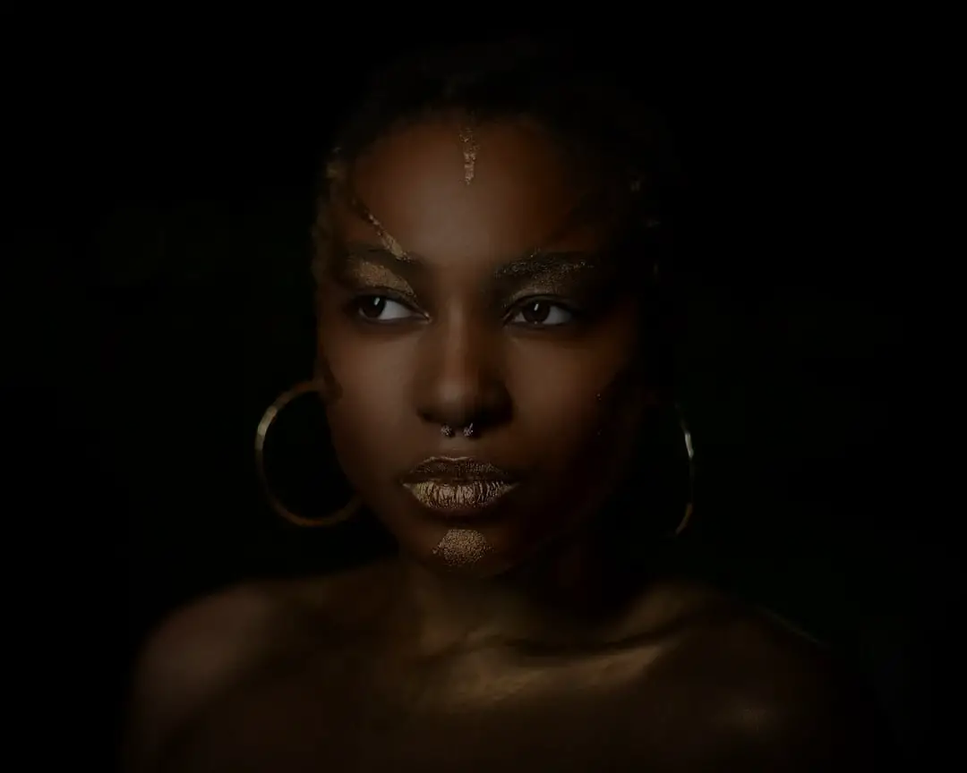 black woman with septum piercing and earrings with dark light