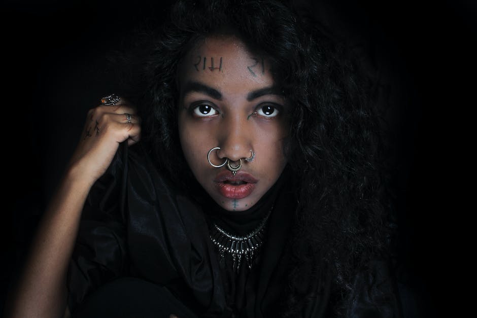 girl with several nose rings and septum piercing on a black background