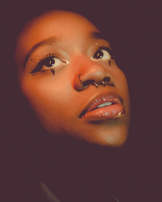 girl with septum piercing and makeup looking up with black background